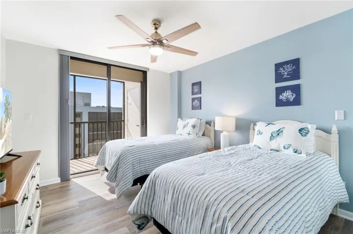 Bedroom featuring wood finished floors, access to outside, ceiling fan, and expansive windows