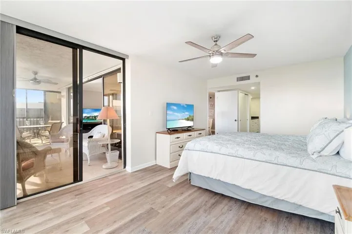 Bedroom with light wood-style floors, ceiling fan, access to exterior, and a wall of windows