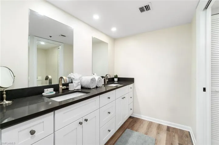 Full bath featuring light wood finished floors, double vanity, recessed lighting, and a closet