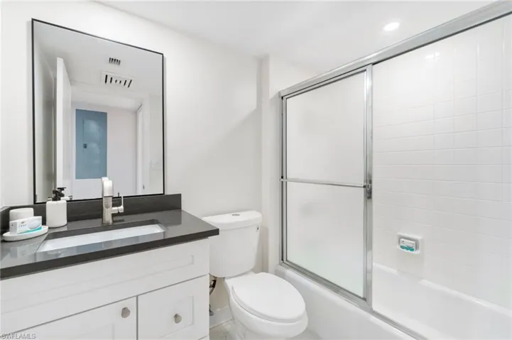 Bathroom featuring combined bath / shower with glass door and vanity