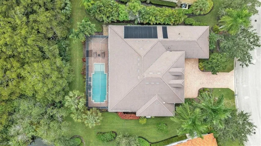 Gable roofline with solar panels, screened-in swimming pool, paved patio, mature landscaping, and a paved driveway for this wonderful custom home offering almost 3000 sq. ft. of living space.