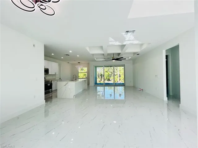 Unfurnished living room with coffered ceiling, beam ceiling, ceiling fan, light marble finish floors, and recessed lighting