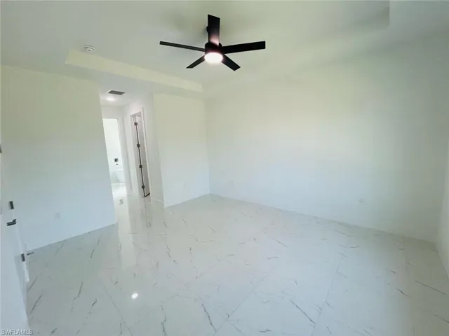Unfurnished room featuring light marble finish flooring and a ceiling fan