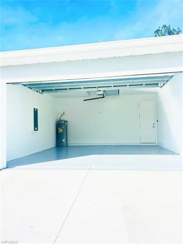 Garage with concrete driveway, electric water heater, and electric panel