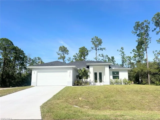 View of front of house featuring a front yard, stucco siding, a garage, and concrete driveway