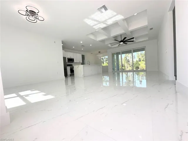 Empty room featuring coffered ceiling, beamed ceiling, light marble finish flooring, a ceiling fan, and recessed lighting