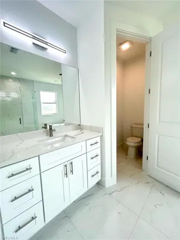 Full bathroom with light marble finish floors, vanity, and a marble finish shower