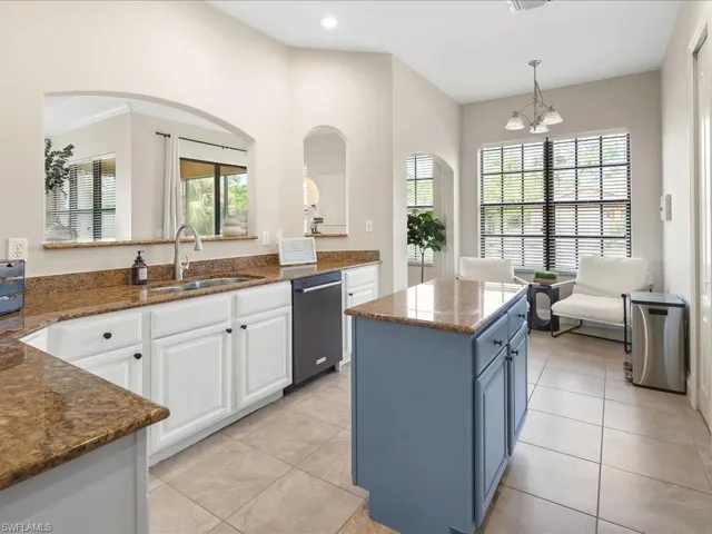 Kitchen with dark stone counters, decorative light fixtures, a center island, light tile patterned floors, and recessed lighting