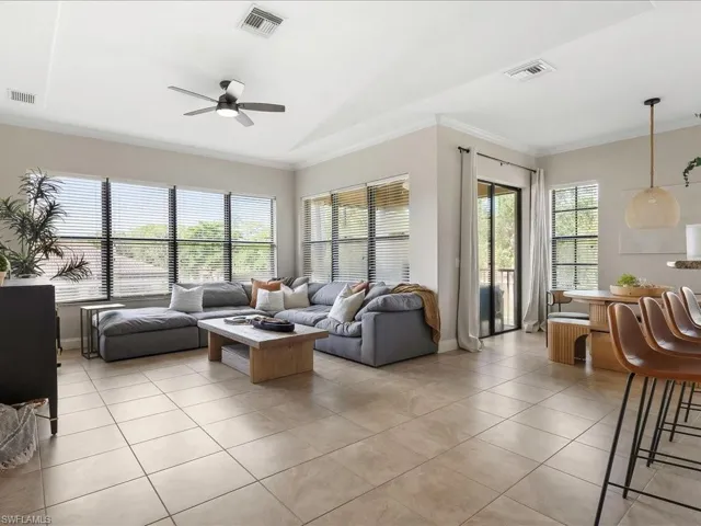 Living room with ornamental molding, light tile patterned floors, and ceiling fan