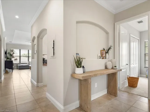Hallway featuring ornamental molding, light tile patterned flooring, plenty of natural light, arched walkways, and recessed lighting