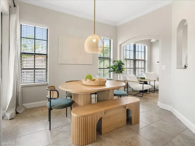 Dining area with ornamental molding and light tile patterned flooring