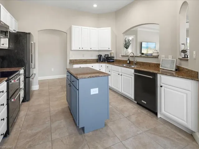 Kitchen with arched walkways, blue cabinetry, stainless steel appliances, white cabinets, and recessed lighting
