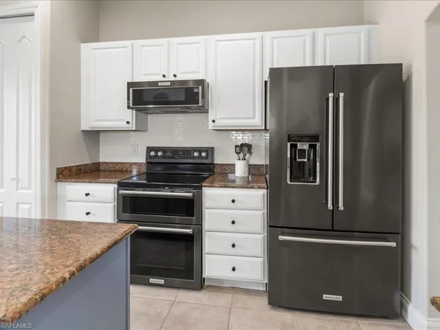 Kitchen featuring appliances with stainless steel finishes, white cabinetry, and light tile patterned flooring