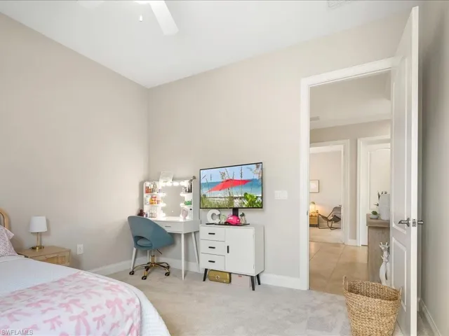 Carpeted bedroom with ceiling fan and tile patterned floors