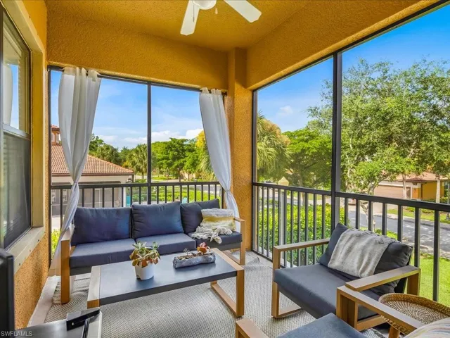 Sunroom with a textured wall, healthy amount of natural light, and view of wooded area