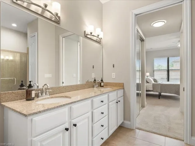Ensuite bathroom with light tile patterned floors and double vanity