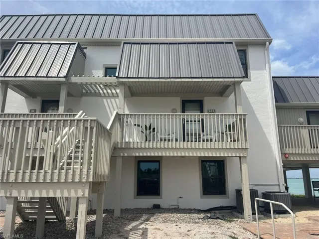 Multi-level structure featuring a metal roof, stucco exterior, and multiple balconies with wood railings
