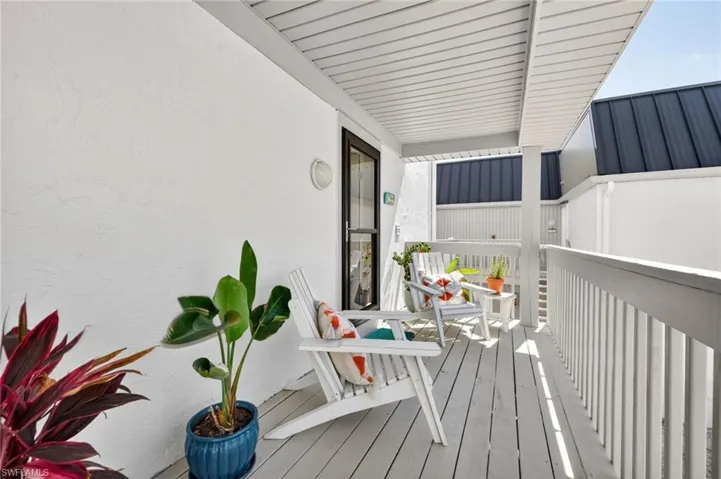 Covered outdoor patio with wood-finish flooring, white railing, and slatted ceiling