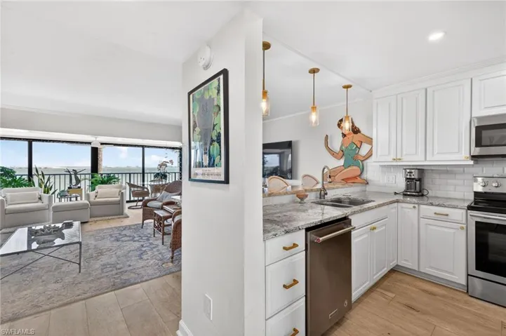 Modern kitchen featuring white cabinetry, granite countertops, subway tile backsplash, and stainless steel appliances