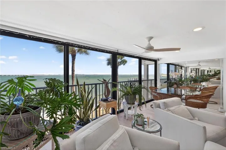 Expansive water views from a glass enclosed lanai with a ceiling fan