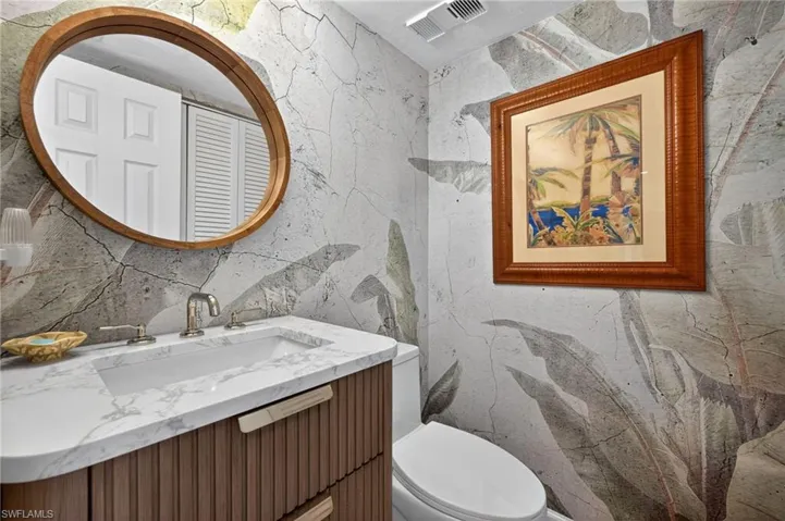 Powder room featuring a sleek vanity with a white marble-look countertop and integrated sink
