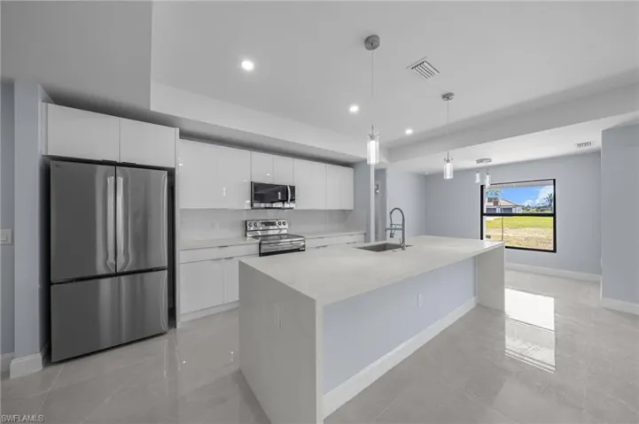 Kitchen with appliances with stainless steel finishes, white cabinetry, light stone countertops, pendant lighting, and recessed lighting