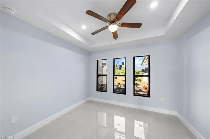 Spare room featuring a tray ceiling, a smoke detector, a ceiling fan, and recessed lighting