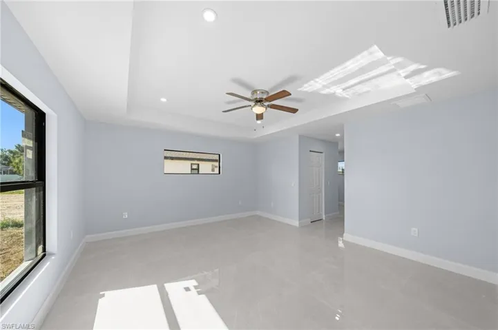 Spare room with a raised ceiling, plenty of natural light, recessed lighting, and ceiling fan