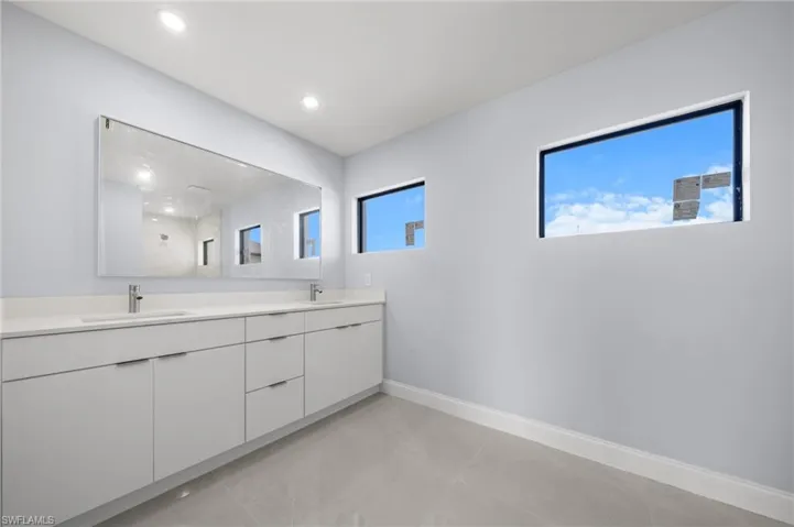 Bathroom featuring double vanity, a shower, recessed lighting, and light tile patterned flooring
