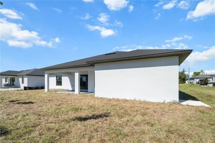 Back of house with a yard, stucco siding, and a patio