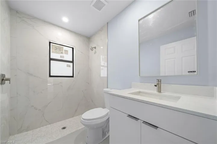 Full bath featuring vanity, a marble finish shower, and recessed lighting