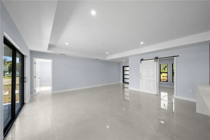 Empty room with a barn door, recessed lighting, and a tray ceiling
