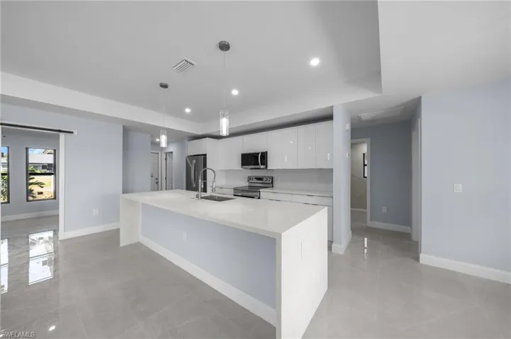 Kitchen featuring stainless steel appliances, white cabinets, recessed lighting, light stone countertops, and pendant lighting