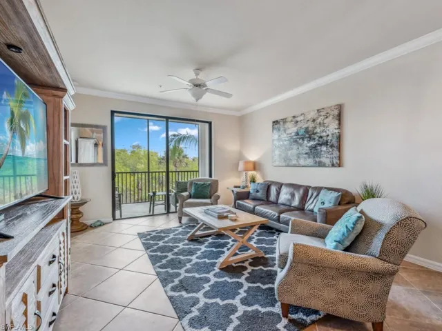Living room with ceiling fan, light tile patterned flooring, and crown molding