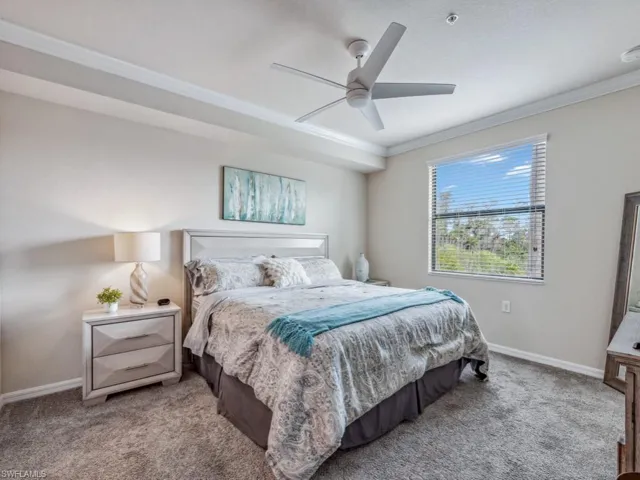 Newly carpeted primary bedroom featuring ceiling fan and crown molding
