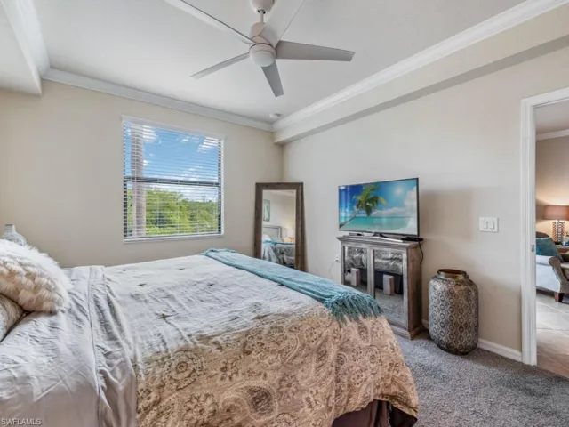 Newly carpeted primary bedroom featuring ceiling fan and crown molding