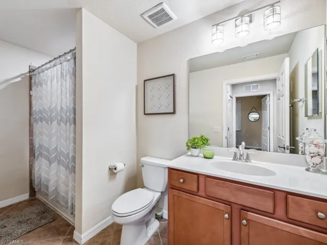 Guest bathroom with toilet, tile patterned flooring, vanity, and curtained shower