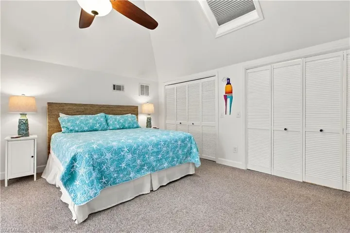 Vaulted ceiling with skylight, wood-finish ceiling fan, recessed lighting, and louvered bifold closet doors