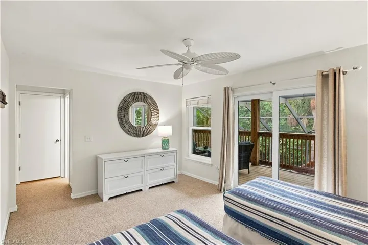 Ceiling fan with light fixture, sliding glass doors to exterior, single pane window, neutral carpet flooring, and white interior doors