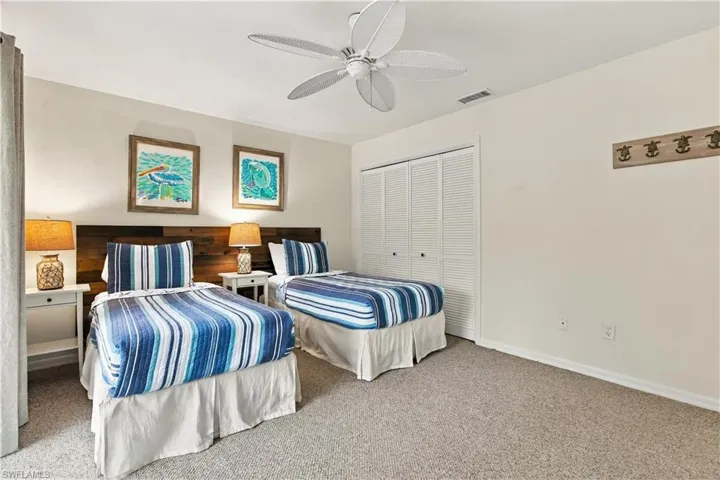 Plank wood-finish headboard, louvered closet doors, and a ceiling fan with integrated lighting