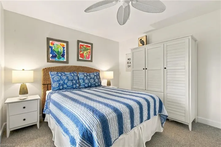 Ceiling fan with white blades, white-painted wood armoire with louvered doors, and light gray wall paint