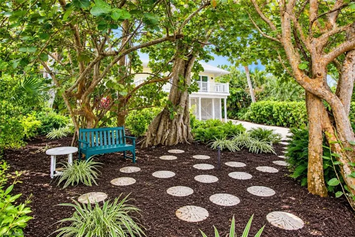 Landscaped garden path with circular pavers, surrounded by mature trees and lush foliage