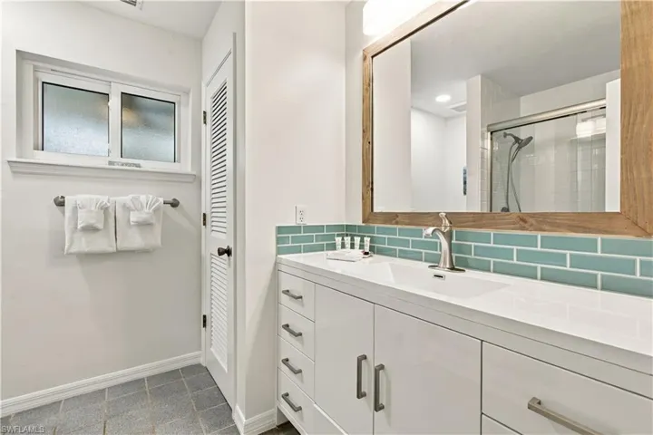 White vanity with an integrated sink and brushed nickel faucet, complemented by a teal subway tile backsplash