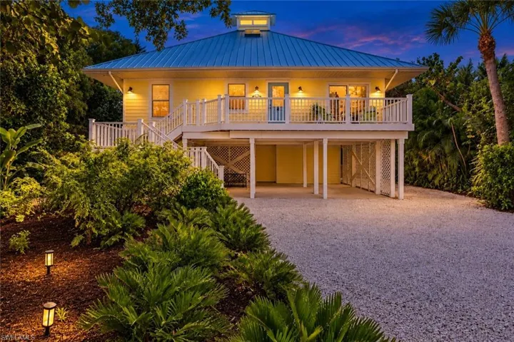 Elevated residence featuring a blue metal roof, yellow siding, and a white balustrade deck