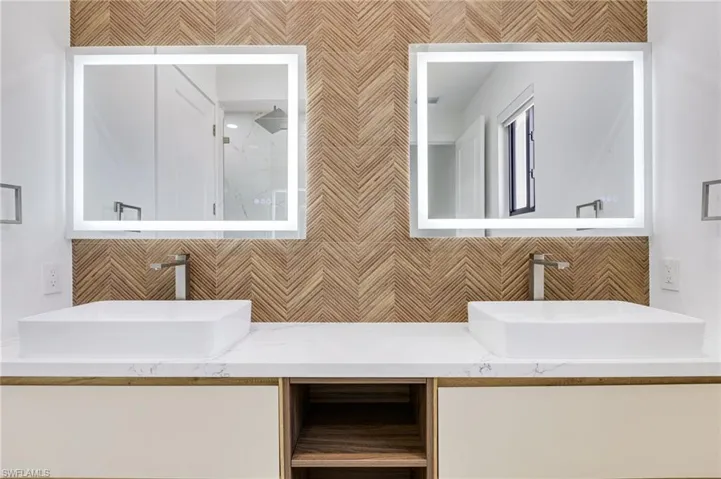 Bathroom with double vanity, a shower, and backsplash