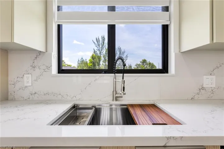 Kitchen view of a sink, backsplash, and white cabinetry
