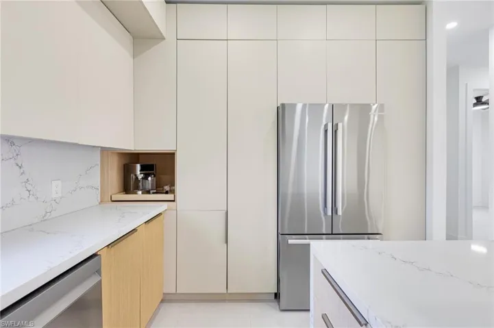 Kitchen with appliances with stainless steel finishes, light stone counters, decorative backsplash, and modern cabinets