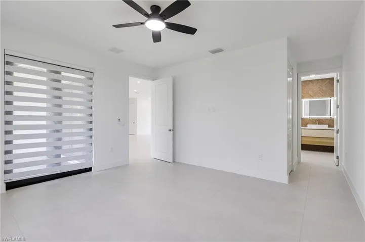 Unfurnished bedroom featuring light tile patterned flooring, baseboards, and ensuite bath