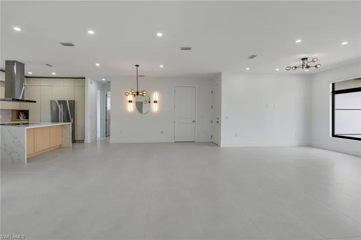 Unfurnished living room with a chandelier, recessed lighting, light tile patterned floors, and baseboards