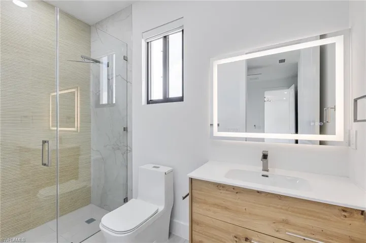 Bathroom with vanity, toilet, and a marble finish shower